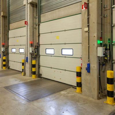 An interior shot of a warehouse with a row of doors and control panels next to it